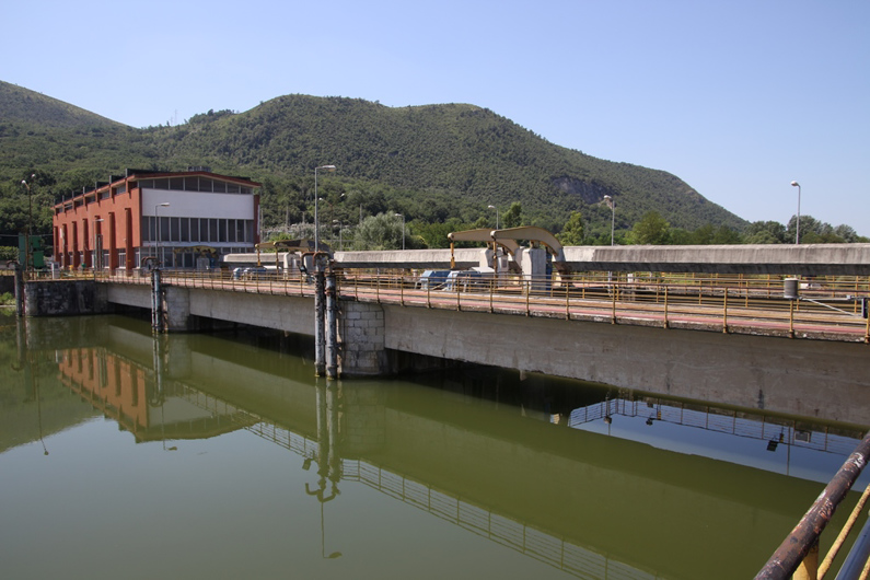 <p>Prospettiva della traversa con sullo sfondo l'edificio della centrale idroelettrica</p>